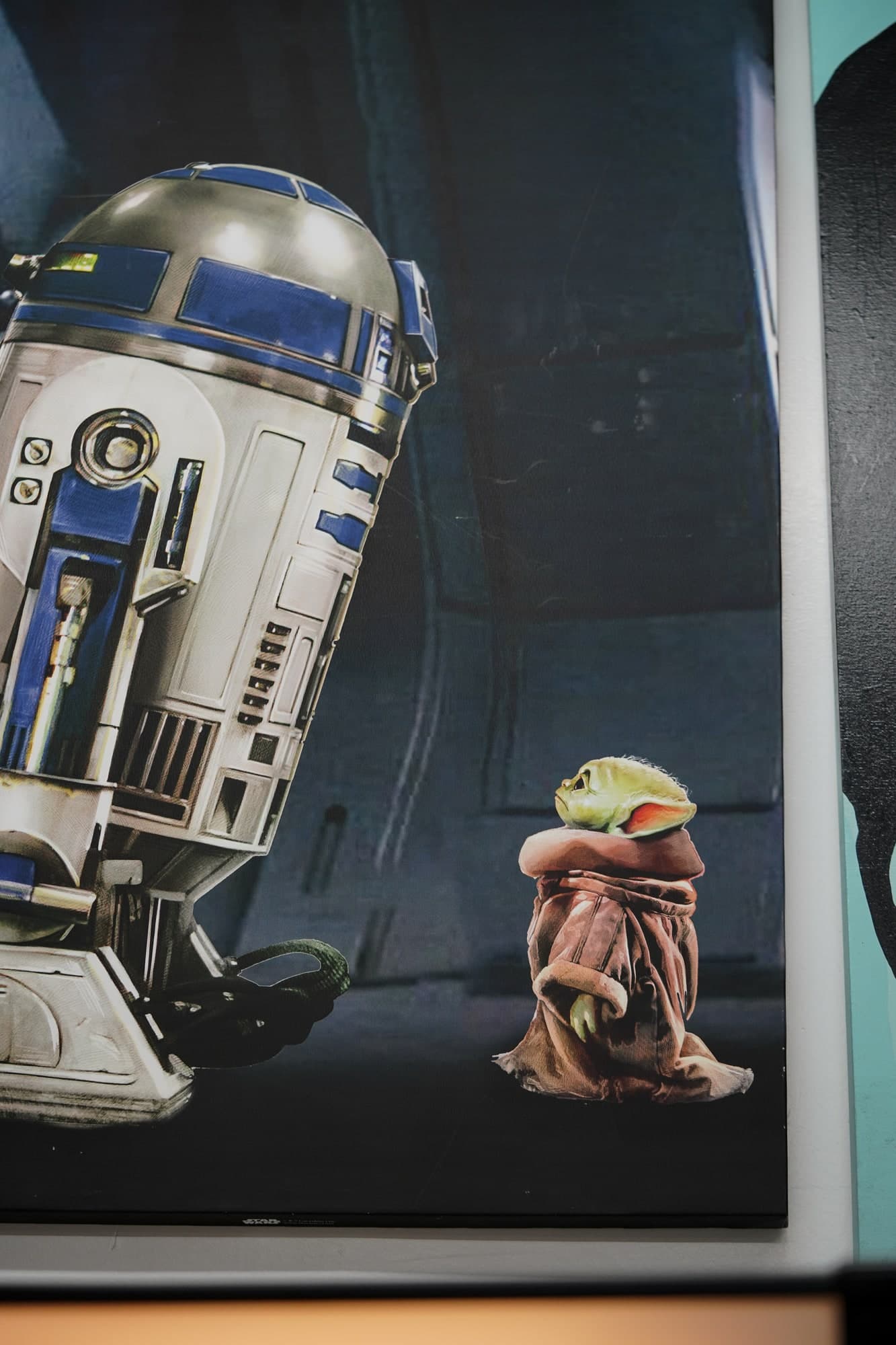 Framed R2-D2 print with a Grogu figure on the parlor's memorabilia shelf